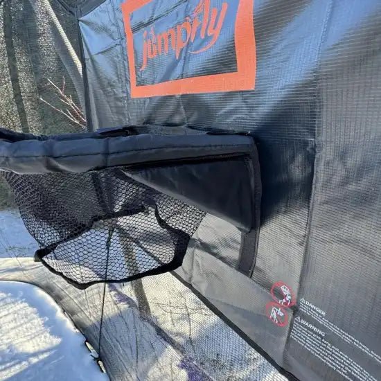 Close-up of Jumpfly trampoline basketball hoop storage net on snowy trampoline.