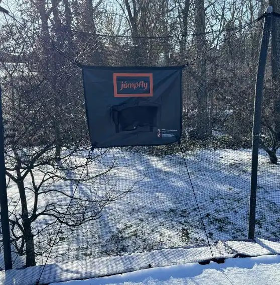 Jumpfly trampoline hoop mounted on a snowy backyard trampoline.